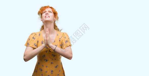 年轻红发妇女用双手乞讨和祈祷图片