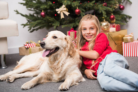 快乐可爱的小孩带着狗躺在圣诞树上图片