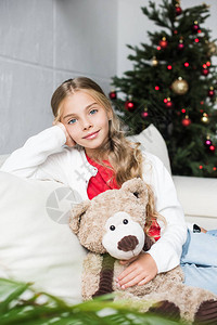 可爱的小孩拥抱泰迪熊坐在圣诞节图片
