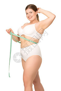 身穿白色内衣的超重女摆姿势测量腰围图片