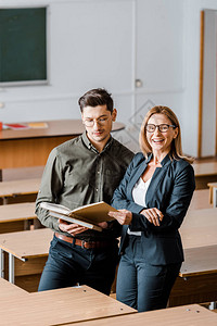 在课堂上持有大学书籍的男学生和微笑着图片