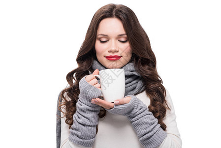 穿着围巾和臂带温暖的年轻美女闻着咖啡味图片