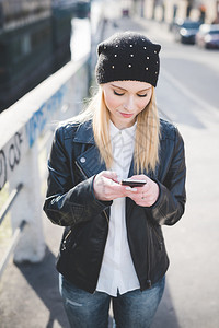 城市中年轻漂亮的金发直女使用智能手机在线连接互联网图片