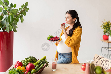 孕妇持有机食品盘子的图片