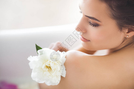 年轻漂亮的女人用鲜花和牛奶洗澡图片
