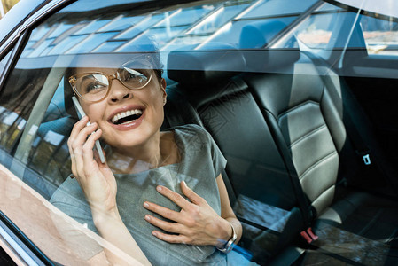 戴着眼镜的快乐女人在汽车里谈论智图片