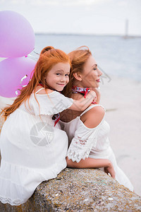 美丽的幸福母亲和女儿与气球拥抱图片
