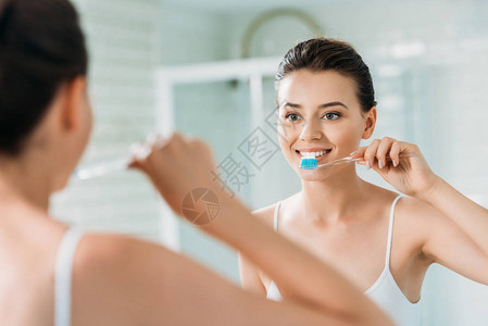 在浴室镜子上刷牙的美丽笑图片