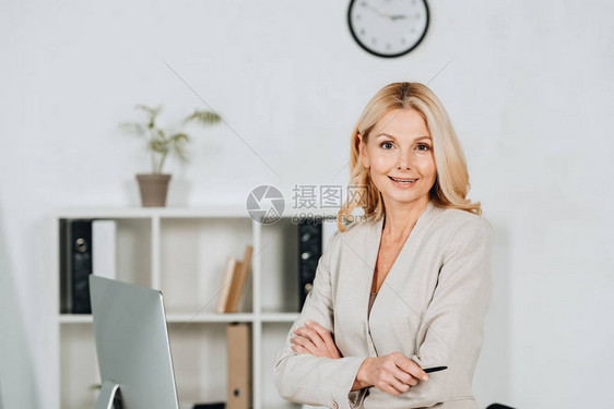 美丽成熟的女商人站在办公室里拿着横臂微笑着脸图片