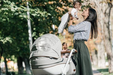 快乐的母亲在公园的婴儿车图片