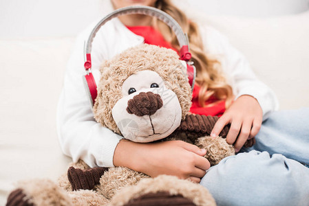 孩子戴着耳机拿着泰迪熊的剪影图片