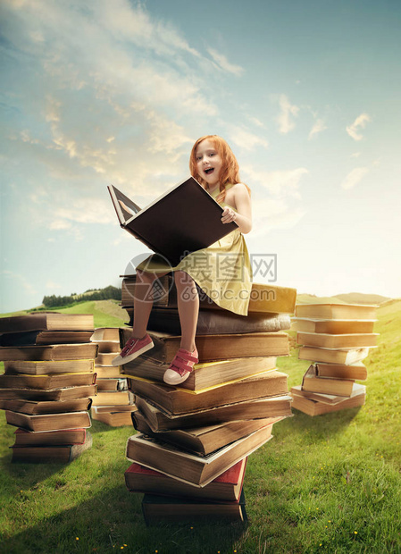 小女孩坐在用大书做成的塔上童年梦想创意和教育理念奇妙的世图片