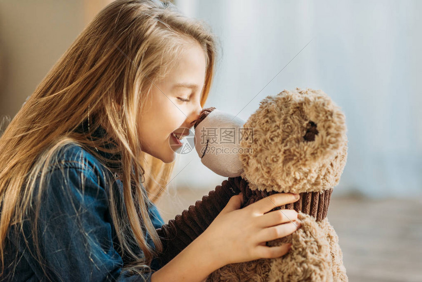 微笑女孩玩泰迪熊的侧视图图片