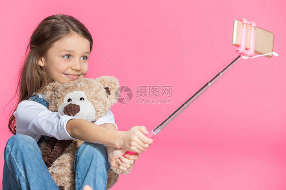 带着泰迪熊微笑的小女孩用粉红图片