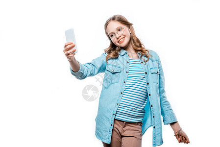 可爱的笑着的少女在眼镜中带着自拍与智能手机图片