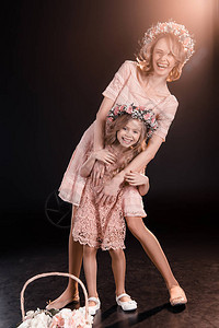 快乐的母亲和女儿在花圈中拥抱图片