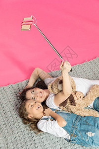 快乐的母亲和女儿一起躺着自拍的高角图片