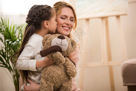 可爱的小可爱孩子抱着泰迪熊在家亲图片