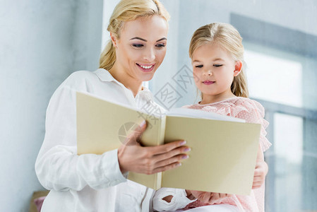 美丽的幸福母亲和女儿在家里一起阅读书的低角度视角图片