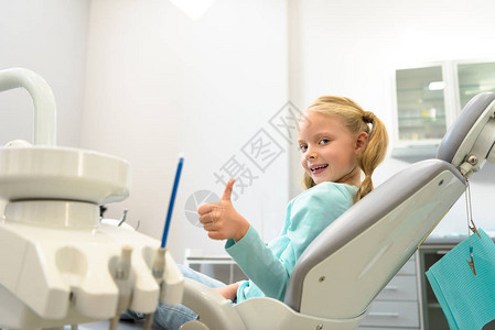 坐在牙医办公室的牙科椅上举起图片