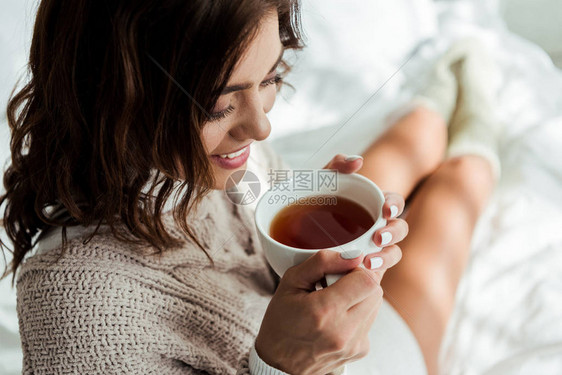穿着灰色毛衣的漂亮女人早上端着一杯茶图片