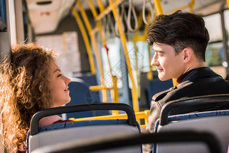 快乐的年轻情侣在公共汽车上互相微图片