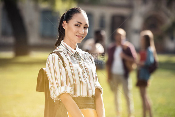 美丽的年轻亚洲女学生在户外站立时图片