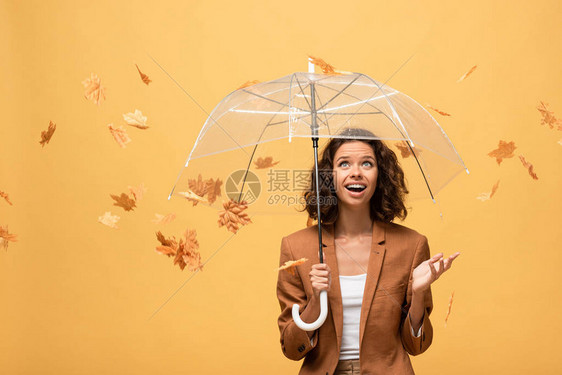 穿着棕色夹克的快乐卷发女人拿着雨伞在坠落的金图片