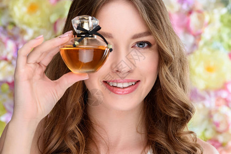 微笑的年轻女子用一瓶香水蒙着一只图片