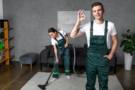 年轻清扫公司工人使用吸尘器清洁工图片