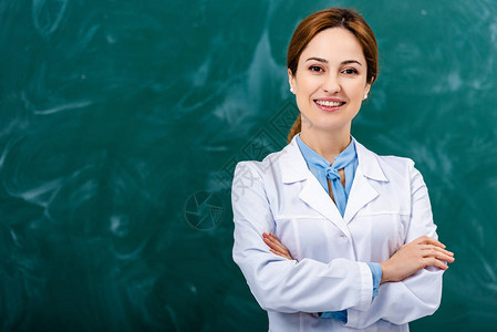 穿着白大衣的微笑化学老师站在黑板前图片