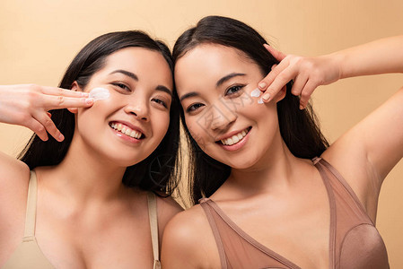 两个快乐的多文化妇女脸上涂化妆奶油看着在蜜蜂上图片