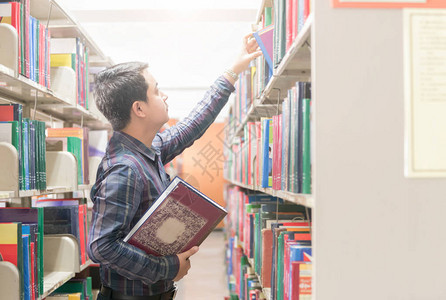 年轻学生在大学图书馆的书架上找书知识教背景图片