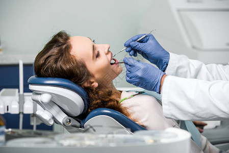 戴着乳胶手套的牙医在牙科诊所检查女图片