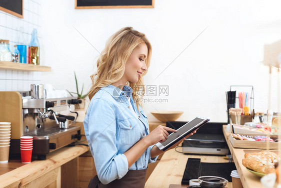 在咖啡馆使用数字平板电脑微笑的年轻女图片