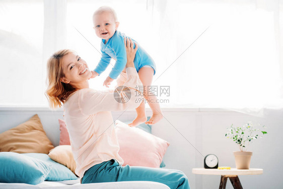 一边笑着的母亲在家中坐在床上一边抚育图片