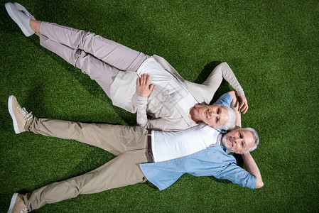 快乐的老年情侣在绿色草地上躺在一起图片