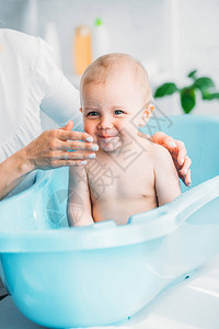 母亲在家中塑料婴儿浴缸中洗小图片