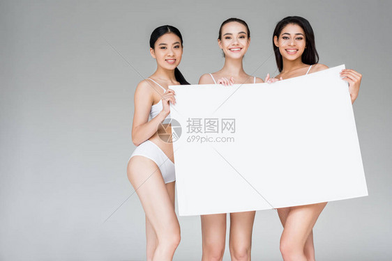 穿着内衣的三位微笑着多文化的女带着灰色背景被孤图片