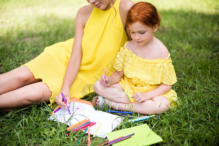 黄裙子中美丽的母亲和女儿的青草镜头图片