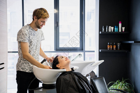 男士美发师洗头客户一位男发型师在美发工作室用淋浴给图片