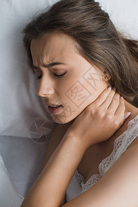 躺床上时颈部疼痛的年轻女图片