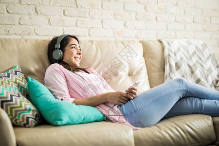 拉丁女人在家里放松听一些音乐在客厅里用耳图片