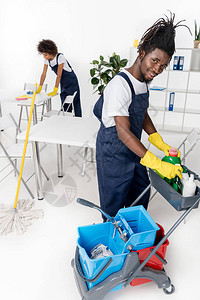 配有清洁设备的专业的非洲青年清洁工共同工作的美国图片