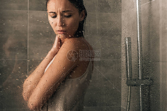 在家中淋浴的美丽悲伤的女子透过玻图片