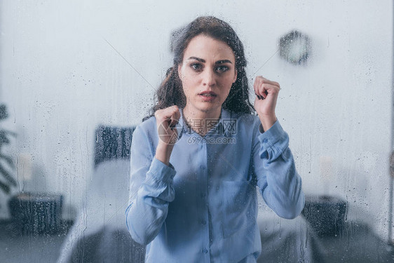 美丽的悲伤的美丽女人手握紧透过窗户用图片