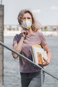 身戴保护面罩的妇女站在书架桥上图片