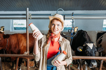 年轻有吸引力的农民拿着瓶装鲜奶和在摊间里笑背景图片