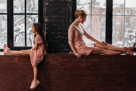 母亲和女儿背靠坐在窗台图片