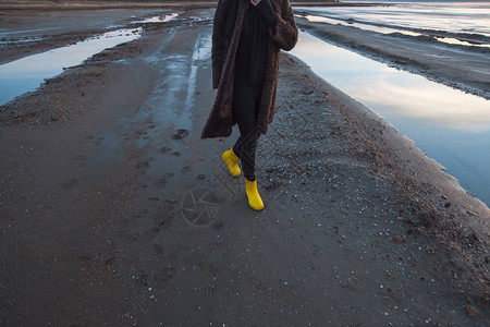 穿着雨靴的漂亮女孩在湖上散步美丽的日图片